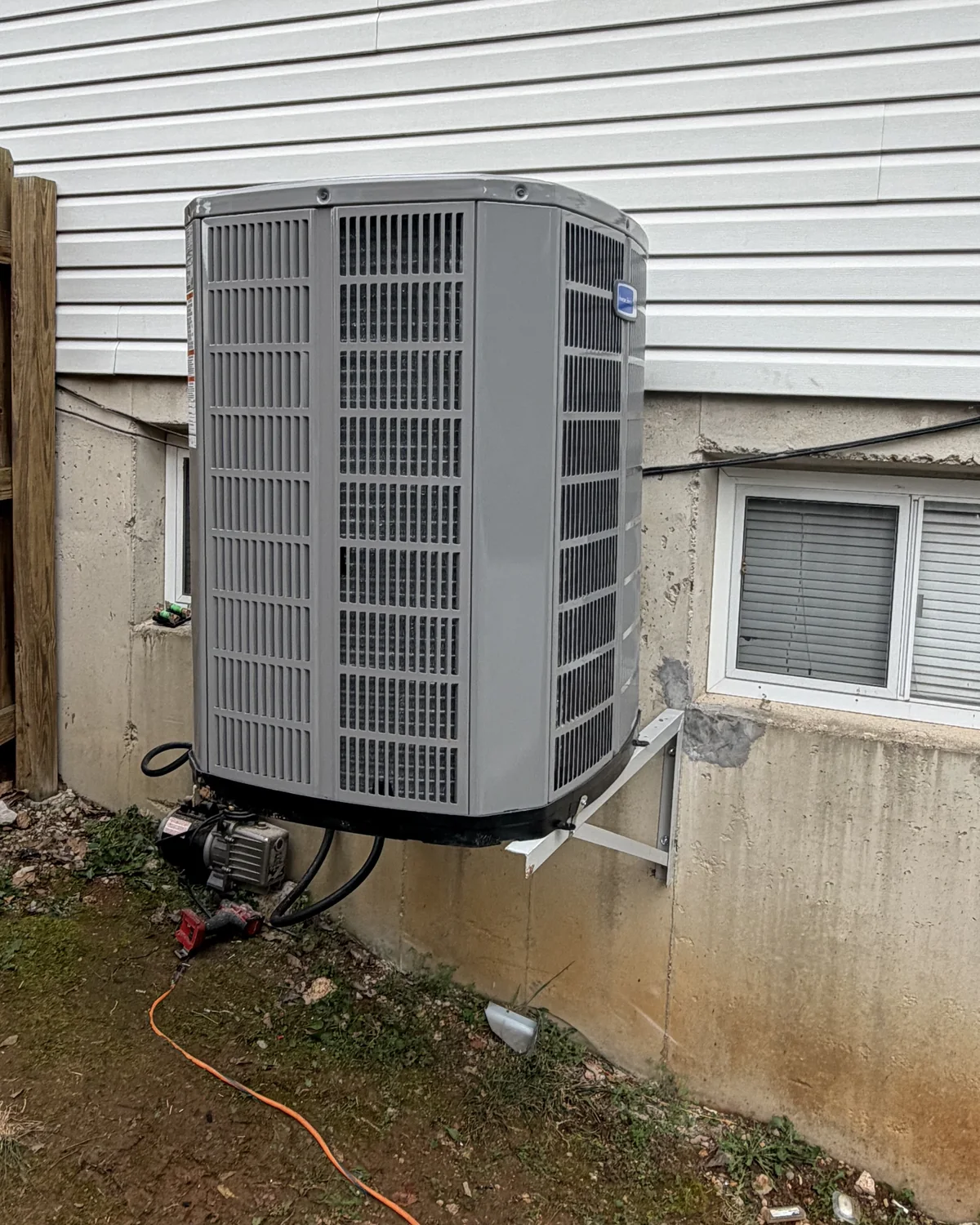 Outdoor HVAC unit on a wall-mounted support with service equipment below