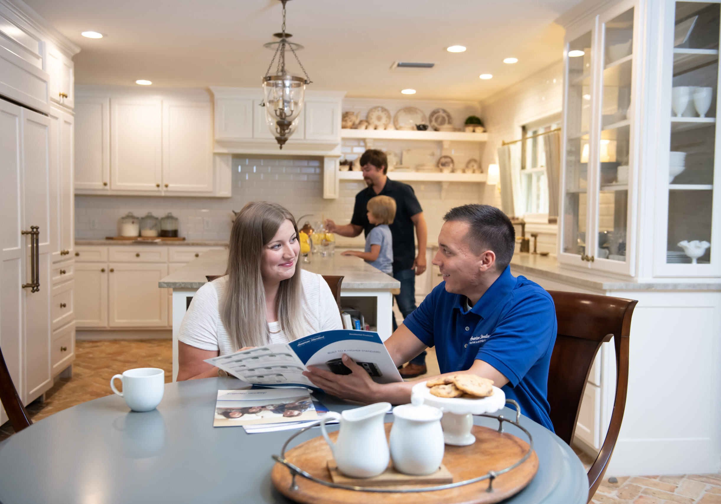 American Standard in discussion with client as her family is busy in the kitchen